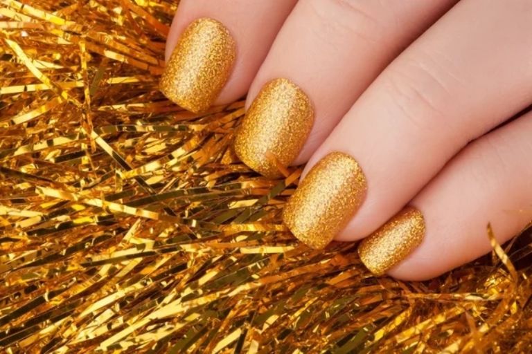 Manicura con brillos en color dorado